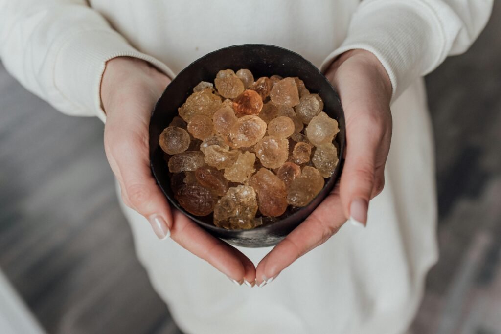A close-up view of hands holding a bowl of natural healing crystals.