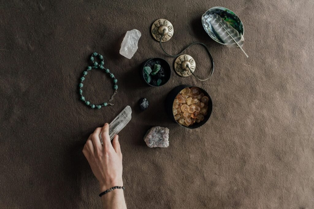 Hand arranging spiritual tools and crystals on a natural brown cloth surface.